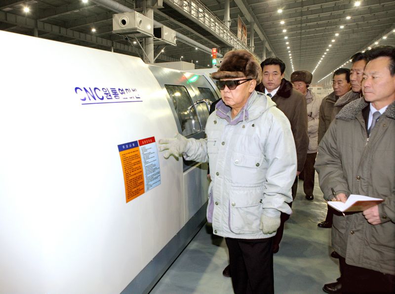Ким Чен Ир ознакомляется со станком с технологией CNC.
Декабрь 99 г. чучхе (2010).