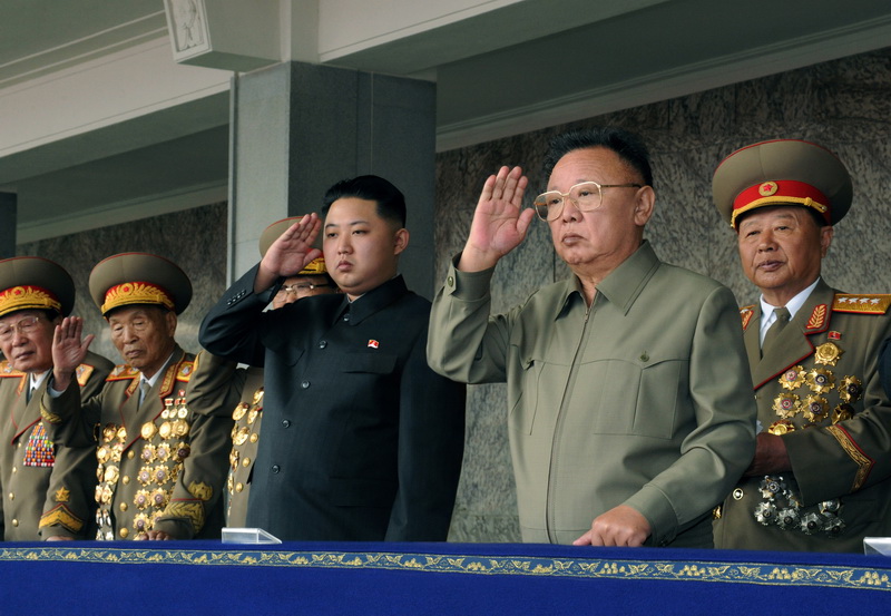 Великий Ким Чен Ир и уважаемый товарищ Ким Чен Ын отвечают на приветствие участников военного парада. Октябрь 2010 года.